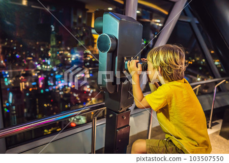 Little boy looks at Kuala lumpur cityscape. Panoramic view of Kuala Lumpur city skyline evening at sunset skyscrapers building in Malaysia. Traveling with kids concept Little boy looks at Kuala lumpur cityscape. Panoramic view of Kuala Lumpur city skyline evening at sunset skyscrapers building in Malaysia. Traveling with kids concept 103507550