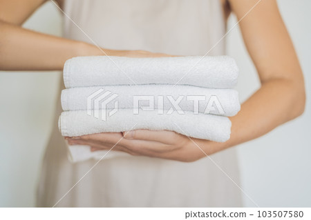 A woman is holding a stack of white towels. Concept of service in hotels, laundry, spa 103507580