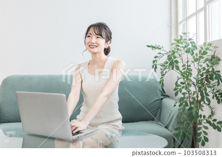 一位女士在客廳放鬆時使用電腦(遠程辦公、遠程工作、在線購物) 一位女士在客廳放鬆時使用電腦(遠程辦公、遠程工作、在線購物) 103508313