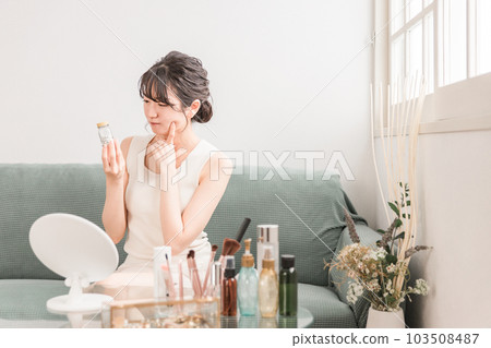 Asian woman with a worried smile holding a bottle of medicine/supplements Asian woman with a worried smile holding a bottle of medicine/supplements 103508487