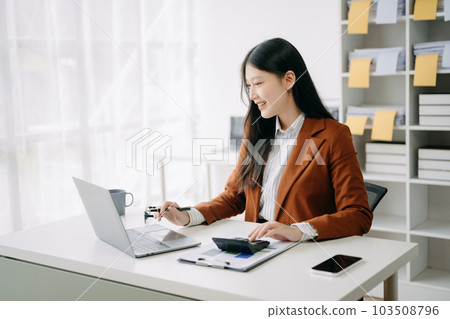 Asian businesswoman working in the office with working notepad, tablet and laptop documents in office Asian businesswoman working in the office with working notepad, tablet and laptop documents in office 103508796