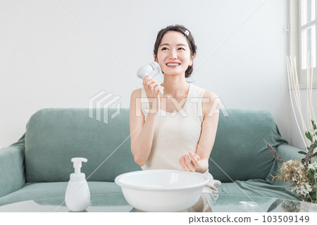 A woman washing her face using a face wash, face wash brush, and face massage brush A woman washing her face using a face wash, face wash brush, and face massage brush 103509149