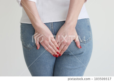Young woman in jeans holds bottom feeling anal pain Young woman in jeans holds bottom feeling anal pain 103509317