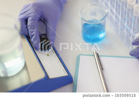 Scientist examines liquids samples in laboratory making note Scientist examines liquids samples in laboratory making note 103509318