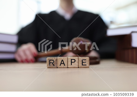 Text Rape on cubes on wooden judge counter in courtroom 103509339