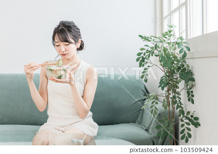 Young Asian woman on a diet eating salad at home (likes and dislikes, troubled, worried) Young Asian woman on a diet eating salad at home (likes and dislikes, troubled, worried) 103509424