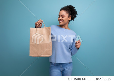 bright brunette afro hair woman holding a gift in an eco-friendly package 103510240