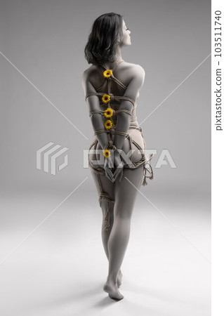 Anonymous naked woman tied with ropes with flowers 103511740