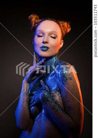 Naughty young naked lady with body art showing painted lips in studio 103511743