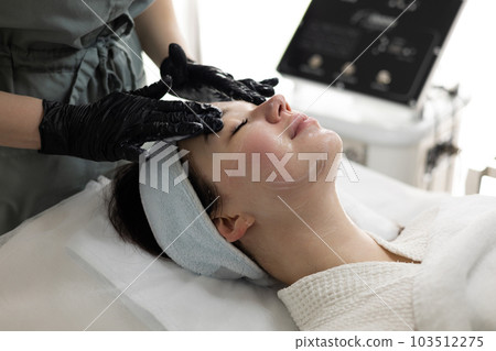Relax woman indulges in a facial treatment at a beauty salon. 103512275