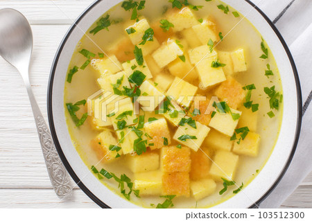 Zuppa imperiale italian soup of chicken broth with parmesan egg dumplings closeup on the plate. Horizontal top view 103512300