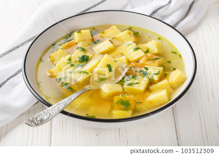 Imperial Soup Zuppa Imperiale is a typical Bolognese soup fluffy semolina dough is baked, then reduced into dices, and cooked with a broth closeup on the plate. Horizontal 103512309