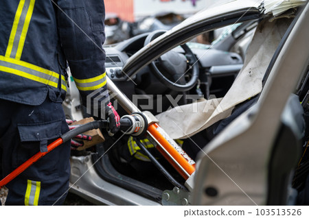 Firefighters using hydraulic tools during a rescue operation training. Rescuers unlock the passenger Firefighters using hydraulic tools during a rescue operation training. Rescuers unlock the passenger 103513526