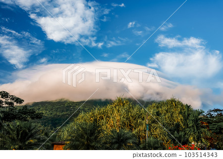 Amazing view of beautiful nature of Costa Rica with cloudy volcano Arenal background. Panorama of volcano Arenal reflected on wonderful picturesque lake, La Fortuna, Costa Rica. Central America. 103514343