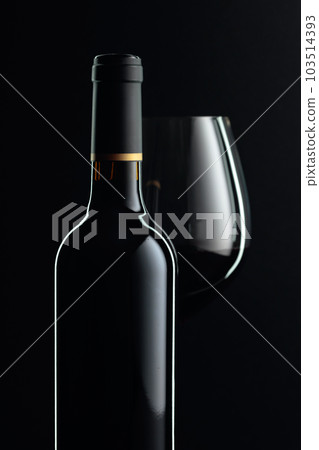 Closed bottle and glass of red wine on a black background. Closed bottle and glass of red wine on a black background. 103514393