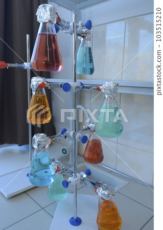 Flasks with colored liquids inside set in the laboratory stand on the worktable, chemical lab Flasks with colored liquids inside set in the laboratory stand on the worktable, chemical lab 103515210