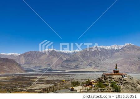 Big Sitting Buddha Statue at Diskit Monastery with Himalaya Range in the back - Nubra Valley, Ladakh, India. 103516051