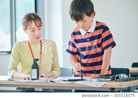 Students practicing calligraphy and a young cram school teacher 103518575