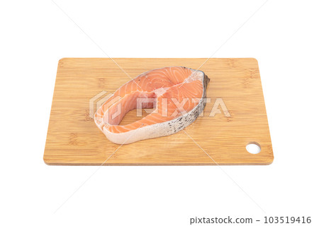 Portioned red fish steak such as salmon or trout on a cutting board. 103519416