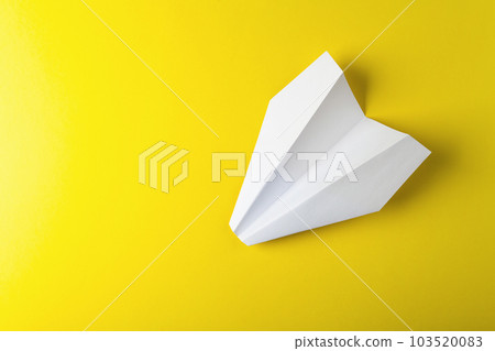 Flat lay of white paper plane on pastel yellow color background 103520083
