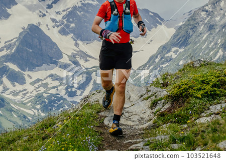 athlete runner running mountain trail skyrunning marathon in background snowy peaks, jogging difficult route race 103521648