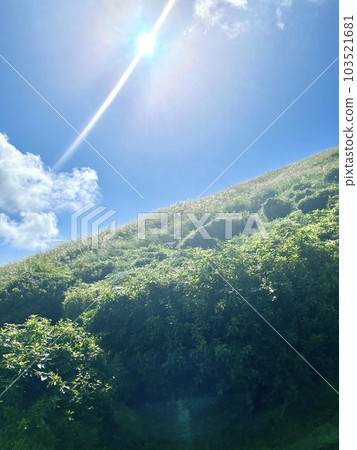 The sun shines strongly on the sky and the slanted hills 103521681