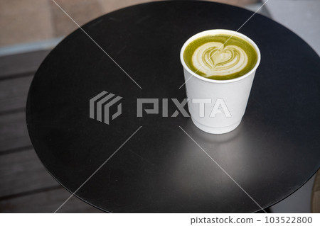 A cup of hot green tea with latte art on the black table A cup of hot green tea with latte art on the black table 103522800