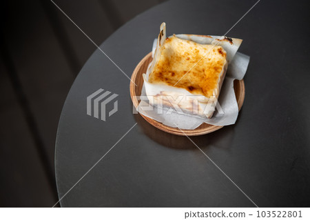 Burnt cheesecake served on wooden plate on the black table Burnt cheesecake served on wooden plate on the black table 103522801