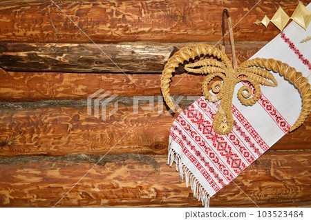 Towel with a traditional Belarusian straw ornament on the background of a wooden wall.  103523484