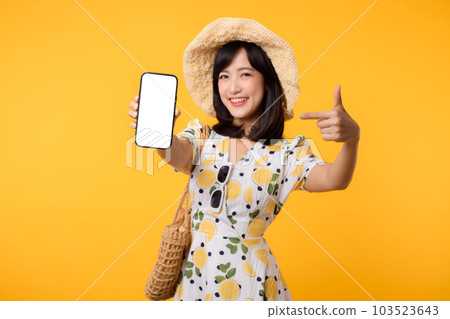 Portrait happy young asian woman with springtime dress fashion showing blank mobile application display screen for advertisement isolated on yellow background. Smartphone app technology concept. 103523643