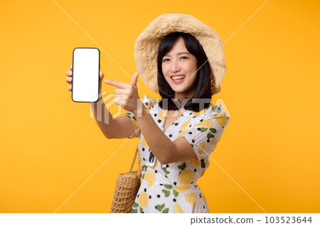 Portrait happy young asian woman with springtime dress fashion showing blank mobile application display screen for advertisement isolated on yellow background. Smartphone app technology concept. 103523644