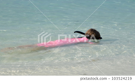 Little girl snorkeling in clear turquoise shallow water on tropical beach. Summer vacation and travel concept Little girl snorkeling in clear turquoise shallow water on tropical beach. Summer vacation and travel concept 103524219