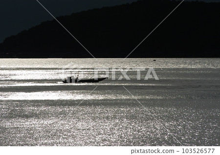 A fishing boat navigating Lake Biwa at dusk 103526577