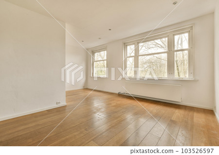 an empty room with wood flooring and large windows looking out to the trees outside in the room is white 103526597