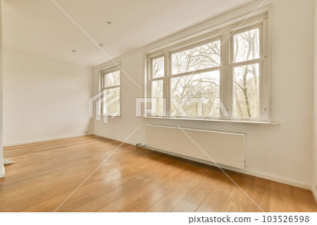 an empty room with wood flooring and large windows looking out onto the trees in the photo is taken from inside 103526598