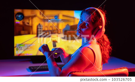 Caucasian woman asks for some more time to play computer in neon light in the dark. Caucasian woman asks for some more time to play computer in neon light in the dark. 103526705
