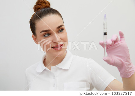 Cosmetologist holds syringe for injection with collagen hyaluronic filler for face or lips rejuvenation Cosmetologist holds syringe for injection with collagen hyaluronic filler for face or lips rejuvenation 103527517