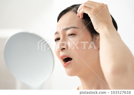 一個女人看著鏡子困擾著 一個女人看著鏡子困擾著 103527638