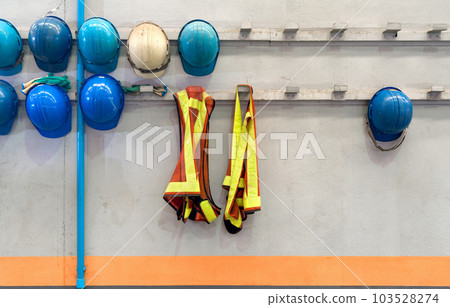 Safety vest and construction hardhat of supervisors and employees hang in front of the factory office shop for safety. Concept of work safety. Building industry. 103528274