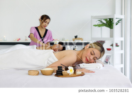 Young asian woman feeling happy and relax during massage. Attractive beautiful girl lying on massage table, getting physiotherapy from masseuse for skin and body care in spa beauty salon. Young asian woman feeling happy and relax during massage. Attractive beautiful girl lying on massage table, getting physiotherapy from masseuse for skin and body care in spa beauty salon. 103528281