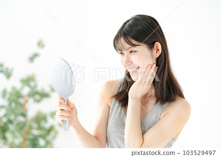 A woman looking at the mirror with a smile Beauty A woman looking at the mirror with a smile Beauty 103529497