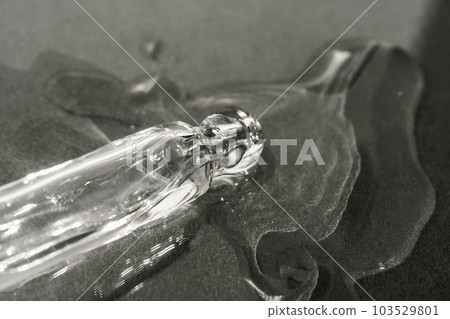The texture of serum or oil with a pipette on a beige background. The texture of serum or oil with a pipette on a beige background. 103529801