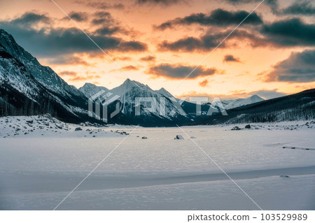 Sunrise over Medicine Lake with rocky mountains and frozen lake in Jasper national park 103529989