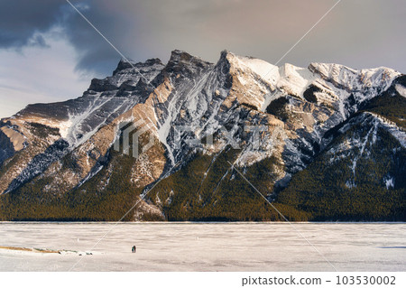 Beautiful frozen Lake Minnewanka with rocky mountains in winter on the evening at Banff national park 103530002