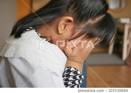 a upset child girl cover her face with hand  103530684