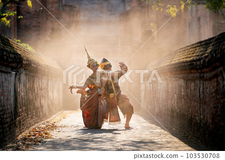 Beautiful Asian woman wear Thai traditional dress action of dancing together with Thai classic mask 103530708