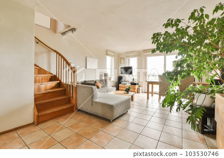 a living room with couches, stairs and plants in the center of the room there is a staircase leading up to the second 103530746