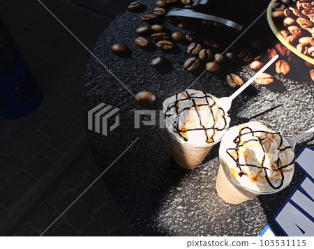 Top view cold coffee frappuccino topped with whipped cream and caramel sauce, refreshing and sweet coffee drink for summer chill out. Stilllife with iced caramel latte coffee in a tall glass Top view cold coffee frappuccino topped with whipped cream and caramel sauce, refreshing and sweet coffee drink for summer chill out. Stilllife with iced caramel latte coffee in a tall glass 103531115
