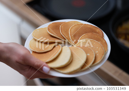 Woman hand holds plate of fresh pancakes Woman hand holds plate of fresh pancakes 103531349