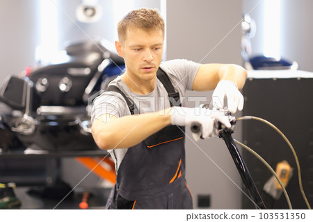 Man inspects motorcycle in repair shop closeup 103531350